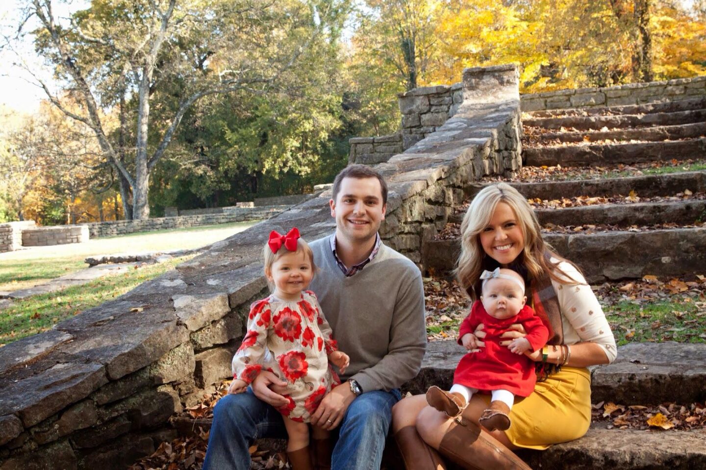 10 Year Wedding Anniversary by popular Nashville lifestyle blog, Hello Happiness: image of a mom, dad, and their two young girls sitting together on some stone steps covered in leaves.