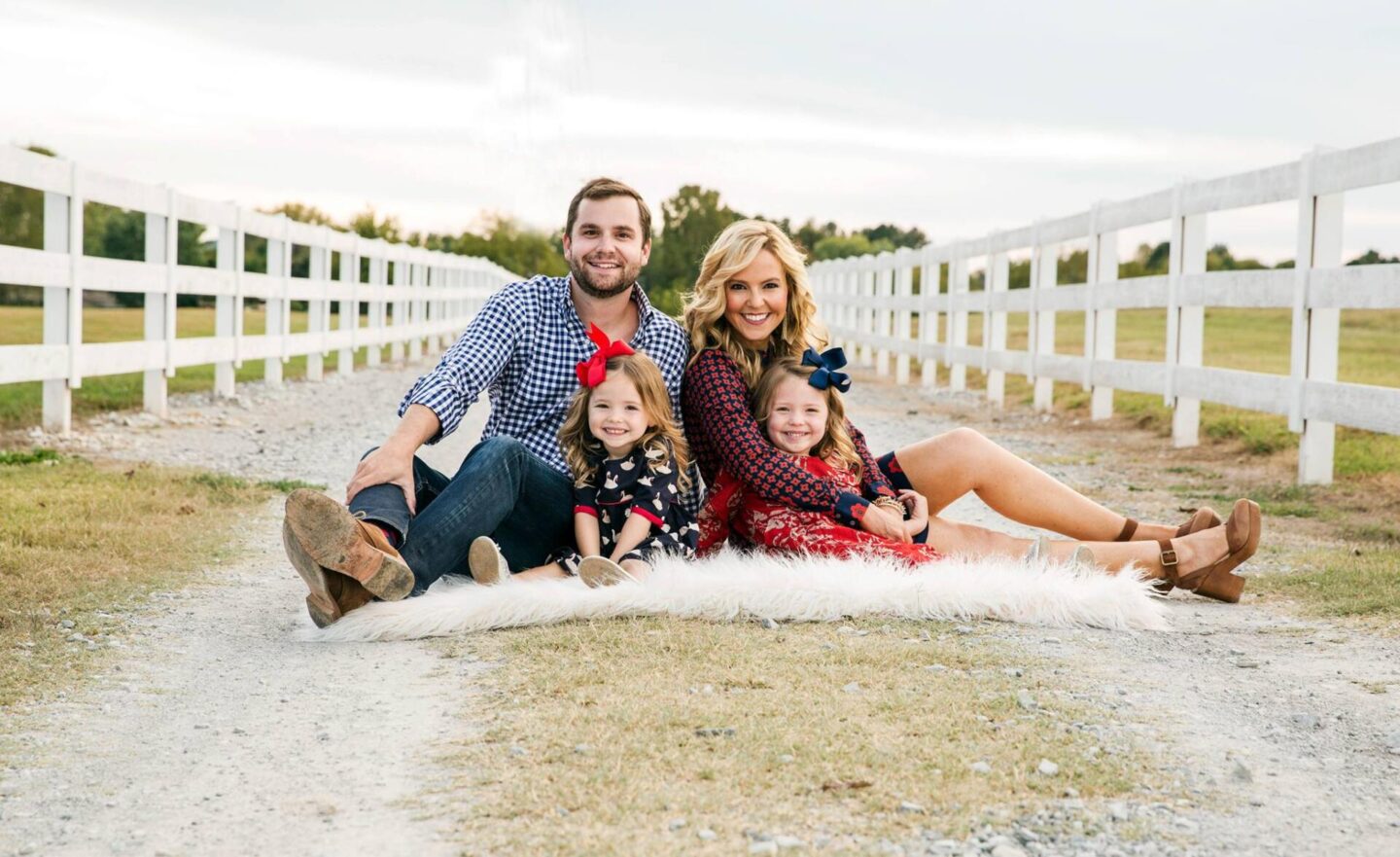 10 Year Wedding Anniversary by popular Nashville lifestyle blog, Hello Happiness: image of a mom and dad and their two young daughters sitting on a white sheepskin rug on a ravel road. 