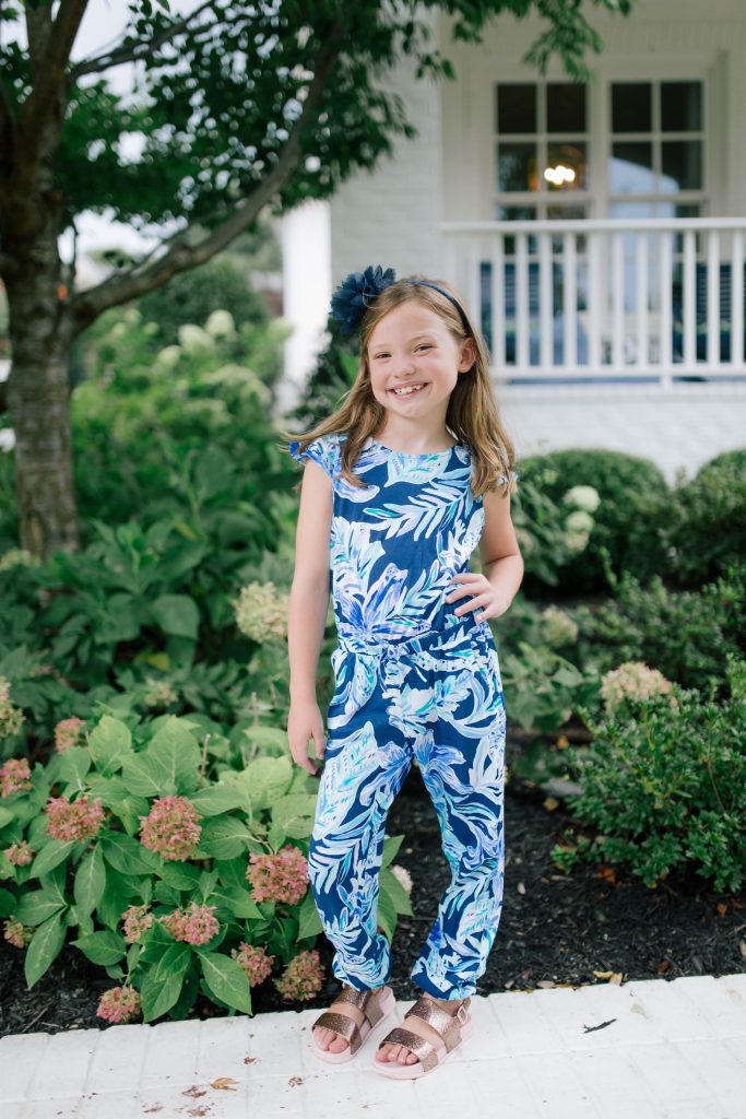 Happy 8th Birthday Daughter by popular Nashville lifestyle blog, Hello Happiness: image of a little girl standing outside and wearing a floral jumpsuit. 