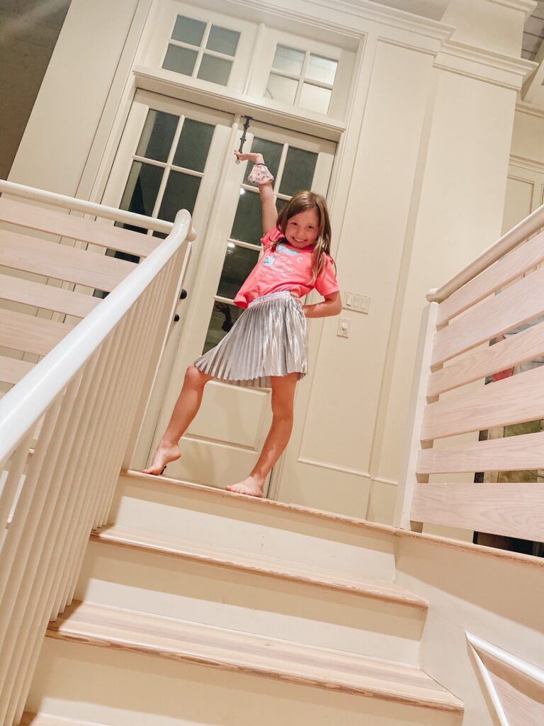 Rosemary Beach by popular Nashville travel blog, Hello Happiness: image of a young girl striking a dnace pose at the top of some stairs. 