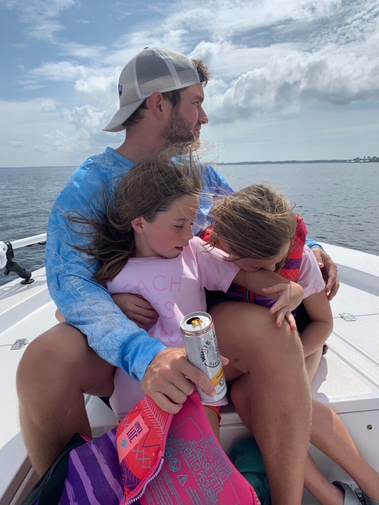 Rosemary Beach by popular Nashville travel blog, Hello Happiness: image of a dad and his two daughters sitting together on a boat. 