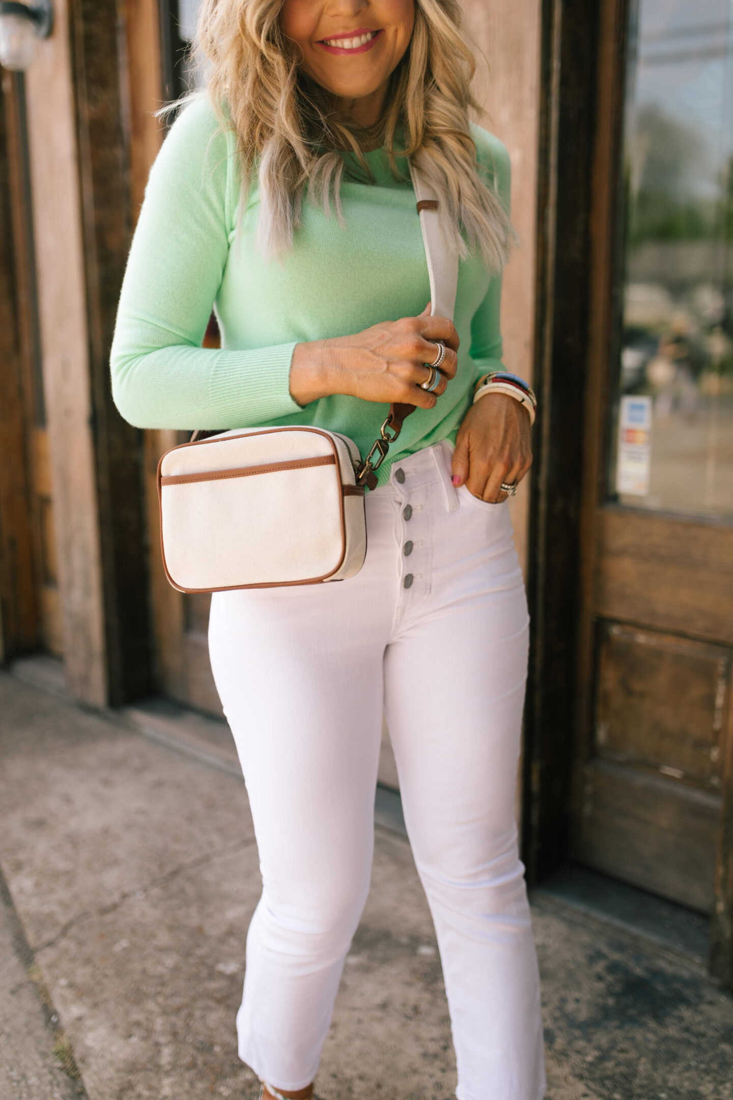 J Crew Clothing by popular Nashville fashion blog, Hello Happiness: image of a woman wearing a J Crew green long sleeve shirt and 10" demi boot crop jean in white with a pair of floral print strap sandals.