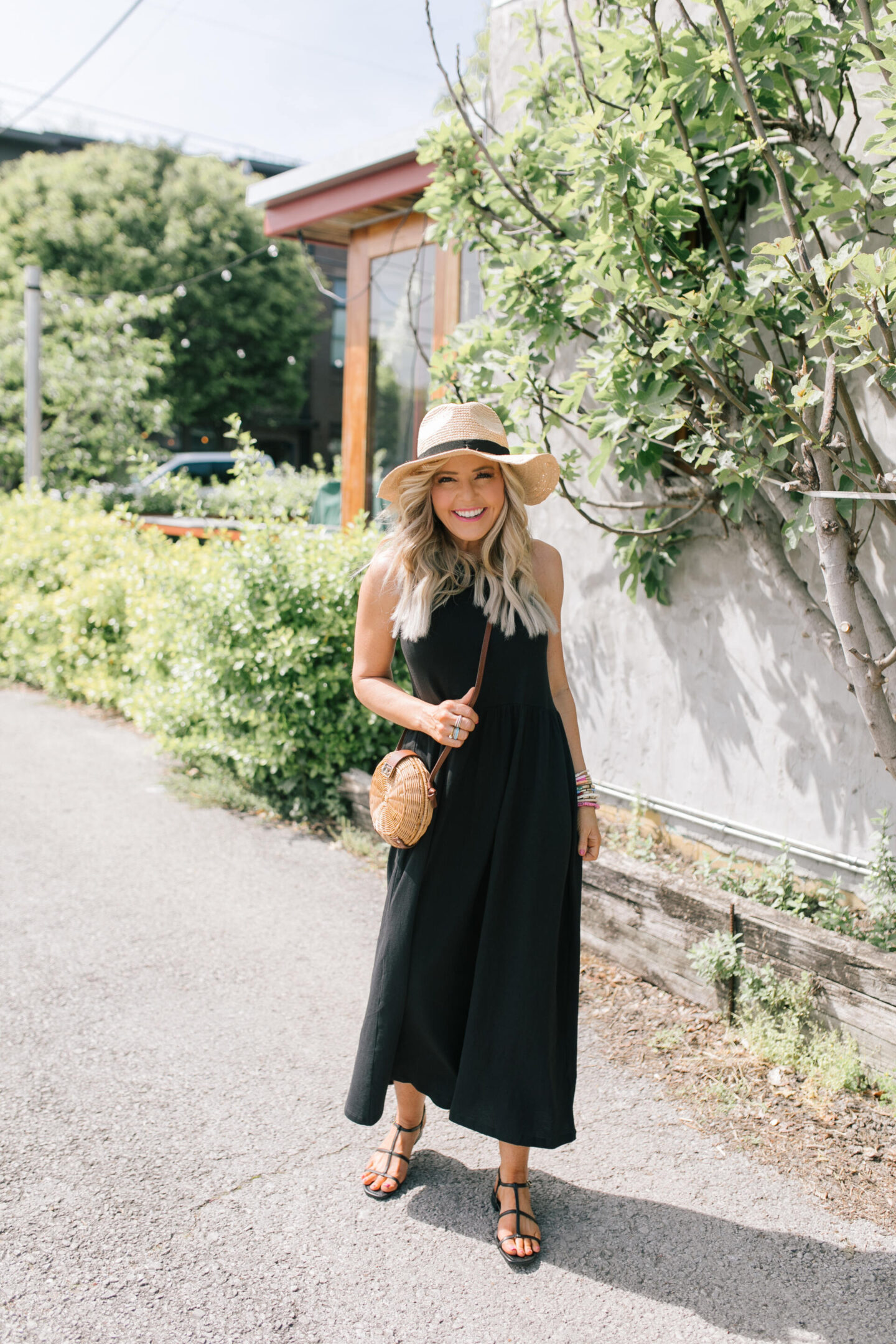 J Crew Clothing by popular Nashville fashion blog, Hello Happiness: image of a woman wearing a black J. Crew sleeveless maxi dress with black strap sandals and a straw sun hat.