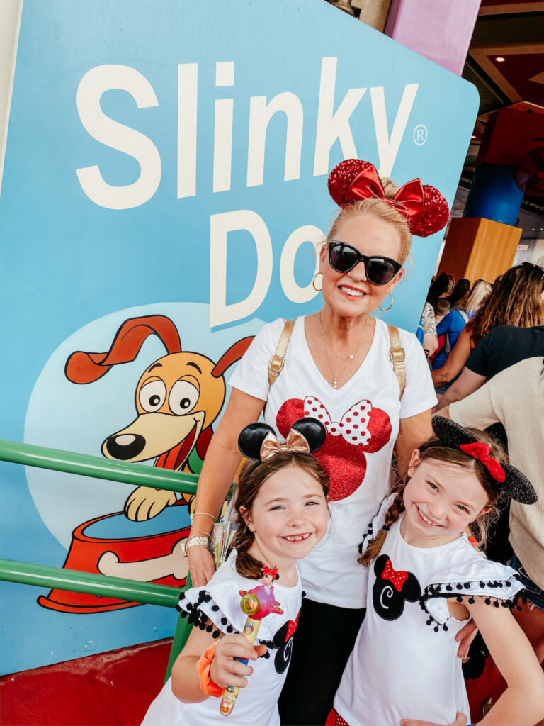 Disney Creators Celebration by poplar Nashville travel blog, Hello Happiness: image of a grandma and her two granddaughters standing in front of a slinky dog sign. 