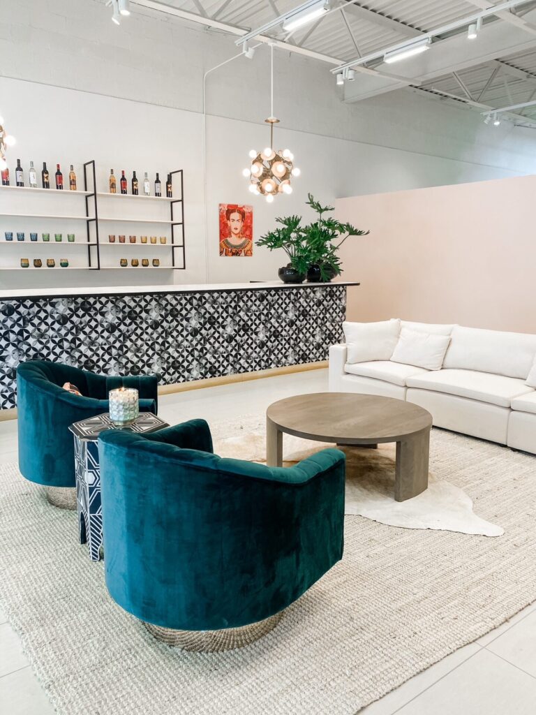 Hotel Crescent Court Dallas by popular Nashville travel blog, Hello Happiness: image of a lounge area with a white couch, blue velvet swivel chairs, round wood coffee table, pink accent wall, black and white bar, and a Frida Kahlo painting. 