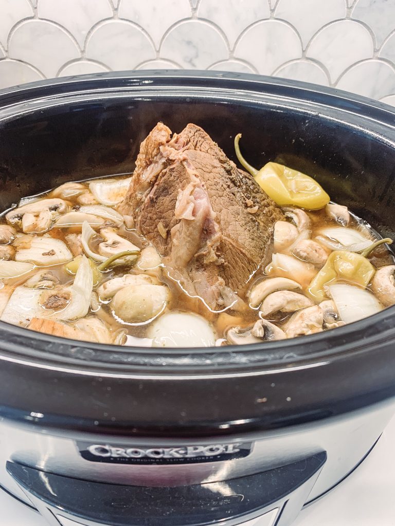 Good Eats | Mississippi Pot Roast Crock Pot Recipe by popular Nashville life and style blog, Hello Happiness: image of a Mississippi pot roast in a crock pot.