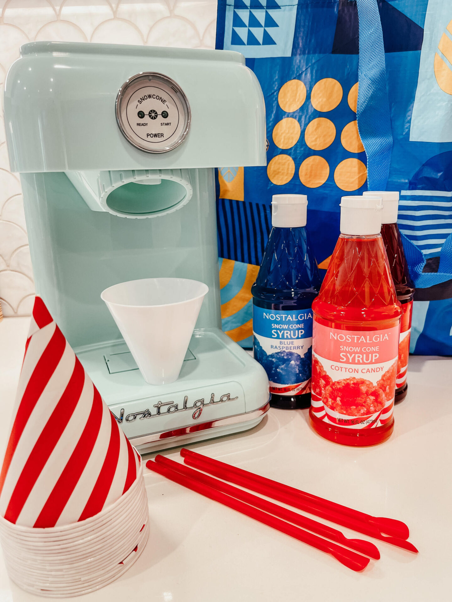 Walmart + Membership by popular Nashville lifestyle blog, Hello Happiness: image of a Nostalgia snow cone machine, stacked red and white stripe paper cups, red straws, and Nostalgia snow cone syrup.
