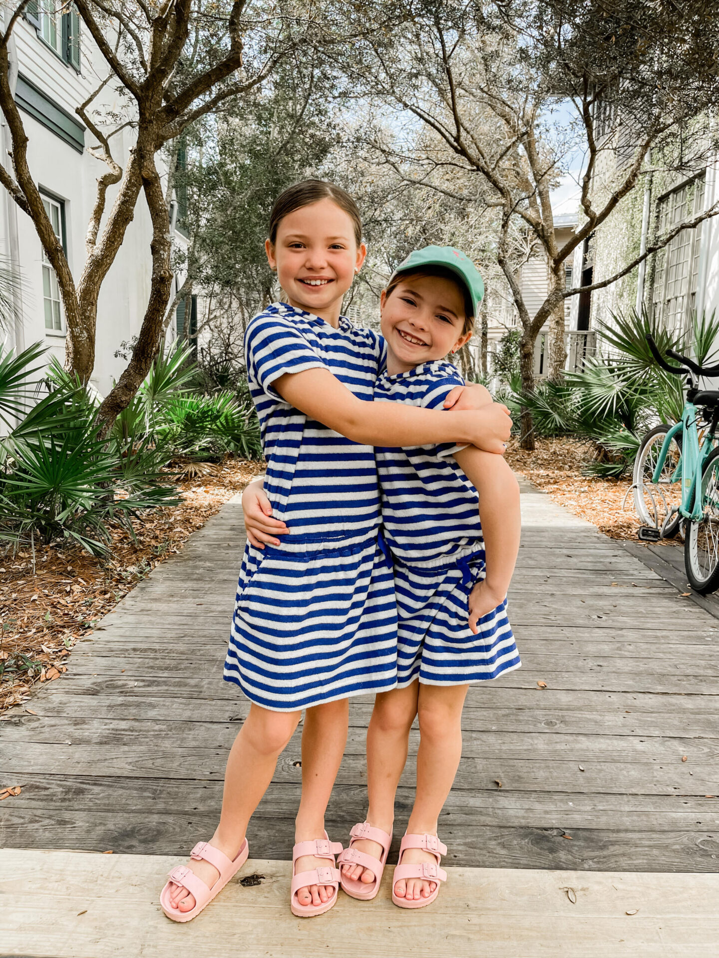 Spring Break Outfits by popular Nashville fashion blog, Hello Happiness: image of two young girls standing together outside and wearing matching striped Terry coverups and pink waterproof sandals. 