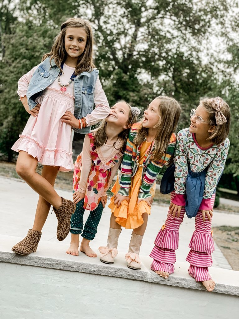 Caroline and Carson's Daily Style... Fall Fashion 2019 Edition by popular Nashville fashion blog, Hello Happiness: image of four little girls standing next to each other outside and wearing a Matilda Jane Clothing Long-Sleeved Lap Dress, Matilda Jane Clothing Leaf Pile Tunic, Matilda Jane Clothing Community Garden Legging, Matilda Jane Clothing Hip And Hygge Cardigan, Matilda Jane Clothing Girls' Lap Dress, Matilda Jane Clothing Tweet Tweet Tunic, and Matilda Jane Clothing First To The Swings Benny.