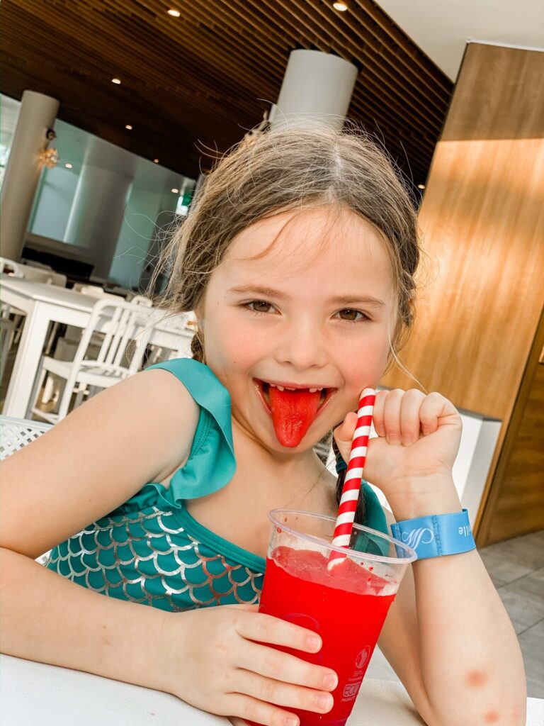 Gaylord Soundwaves by popular Nashville lifestyle blog, Hello Happiness: image of a little girl drinking a red slush drink with a red and white striped straw. 