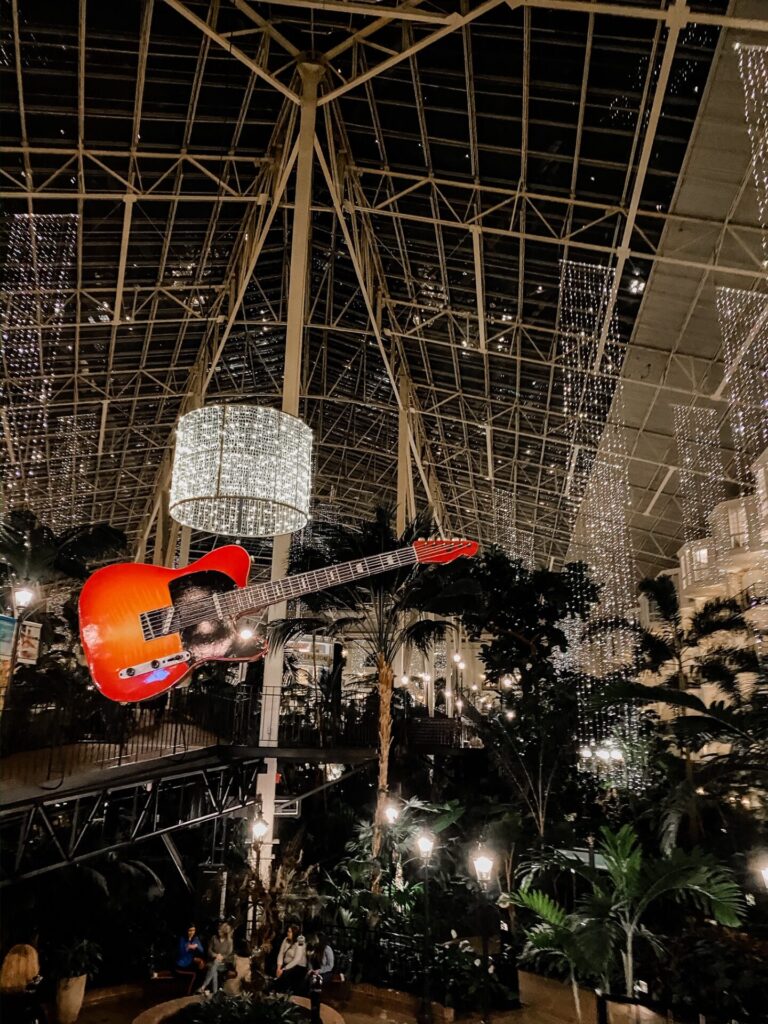 Gaylord Soundwaves by popular Nashville lifestyle blog, Hello Happiness: image of the Gaylord Opryland Resort lobby that's filled with palm trees, crystal chandeliers, and a hanging electric guitar. 