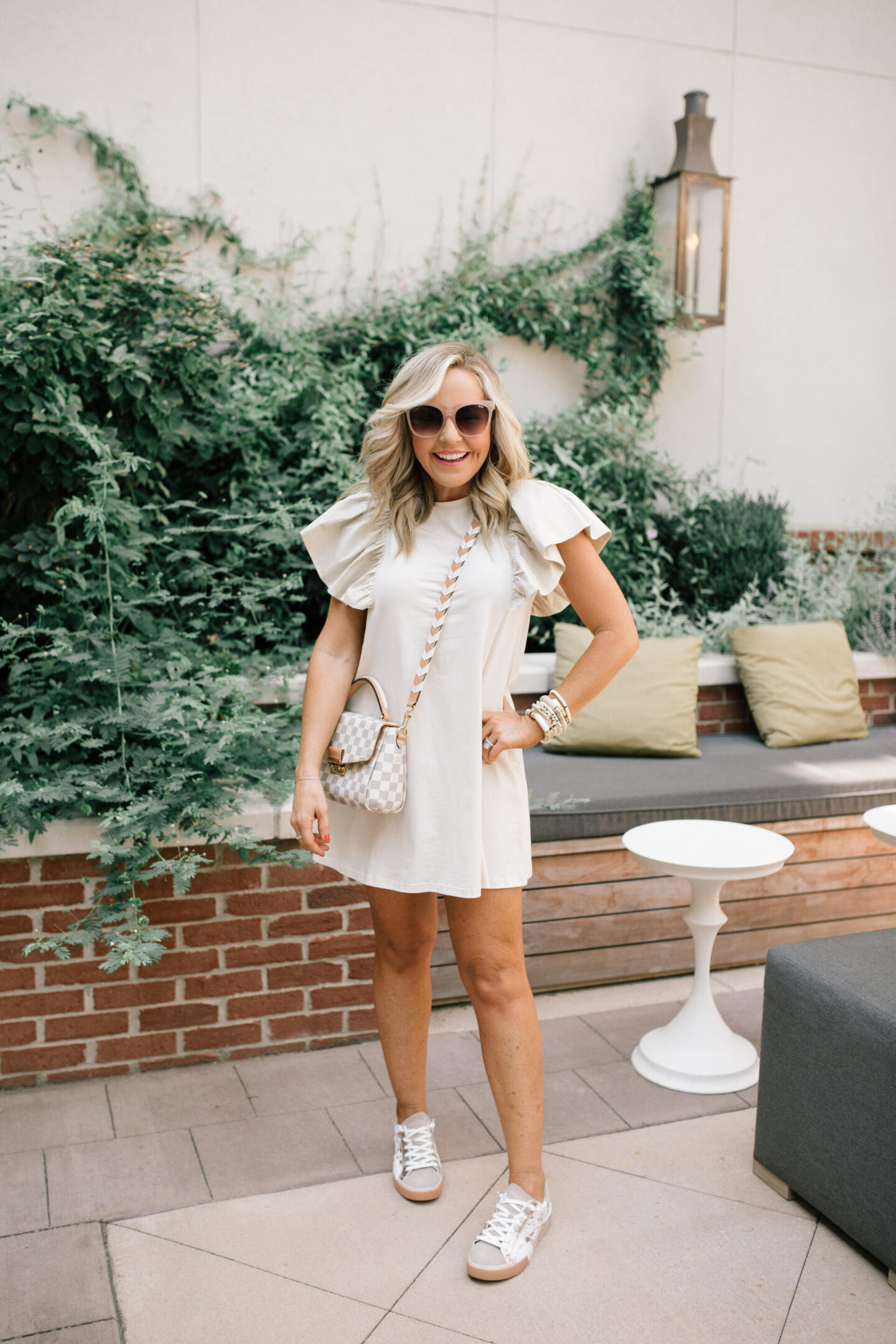 Harpeth Hotel by popular Nashville travel blog, Hello Happiness: image of Natasha Stoneking wearing a cream accentuated sleeve mini dress, tan frame sunglasses, and sneakers at the Harpeth Hotel. 