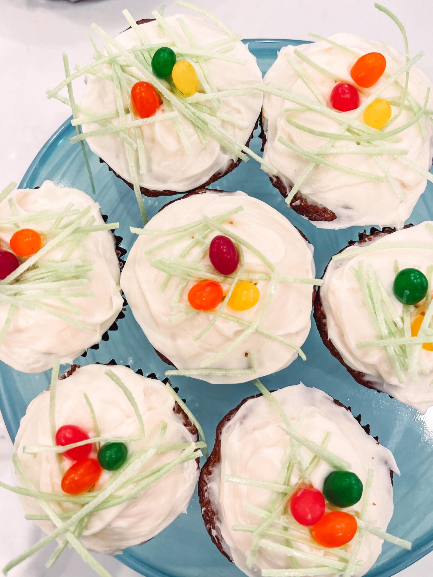 Carrot Cake Cupcakes by popular Nashville lifestyle blog, Hello Happiness: image of cupcakes with white frosting, jelly beans, and green coconut flakes.