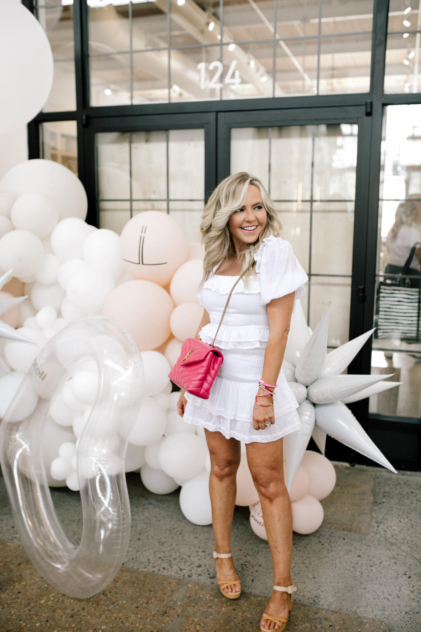 Revolve Clothing by popular Nashville fashion blog, Hello Happiness: image of Natasha Stoneking standing by a white balloon garland and wearing a white Revolve dress and holding a pink YSL bag.