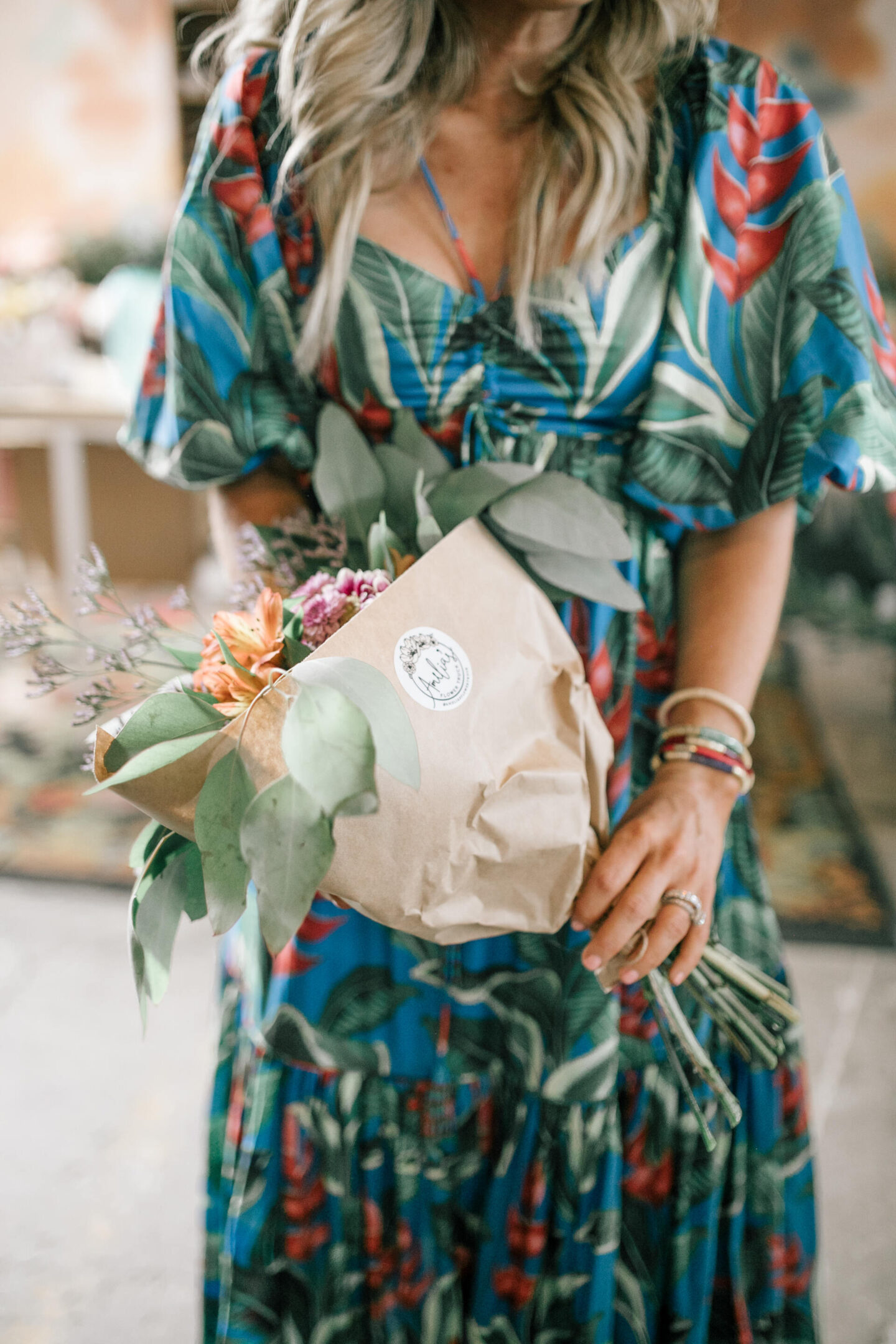 Birthday Wishlist by popular Nashville life and style blog, Hello Happiness: image of a woman wearing a Dream Garden midi dress and holding a bouquet of flowers.