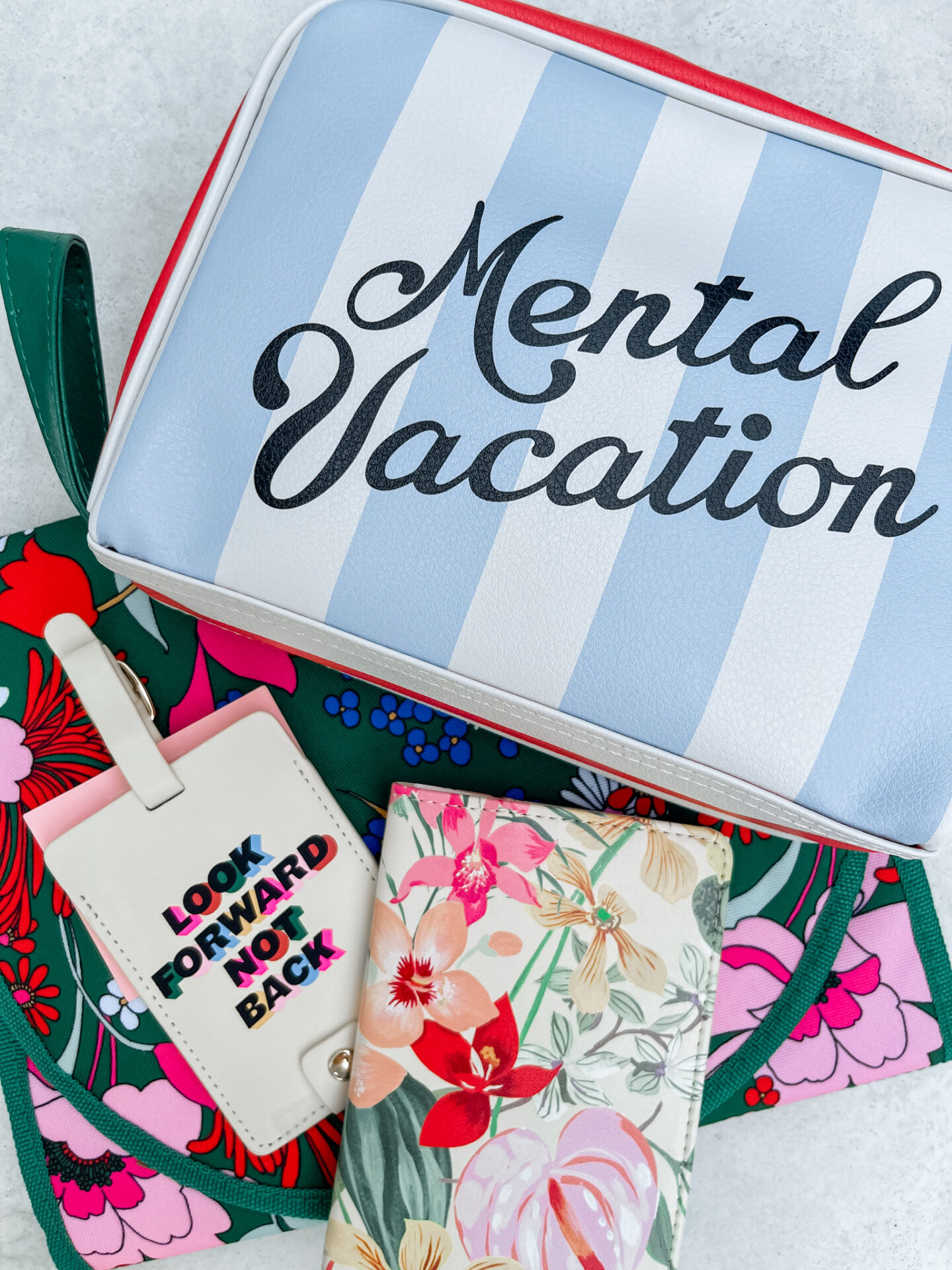 Traveling With Kids by popular Nashville travel blog, Hello Happiness: image of a floral print passport holder, and blue and white stripe bag.