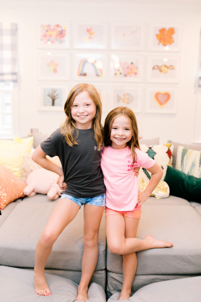 Tween Fashion by popular Nashville fashion blog, Hello Happiness: image of two girls wearing a Target sports bra, Target gym shorts, Target Good Vibes t-shirt, Target Girl Power t-shirt, and standing next to each other on a grey couch.