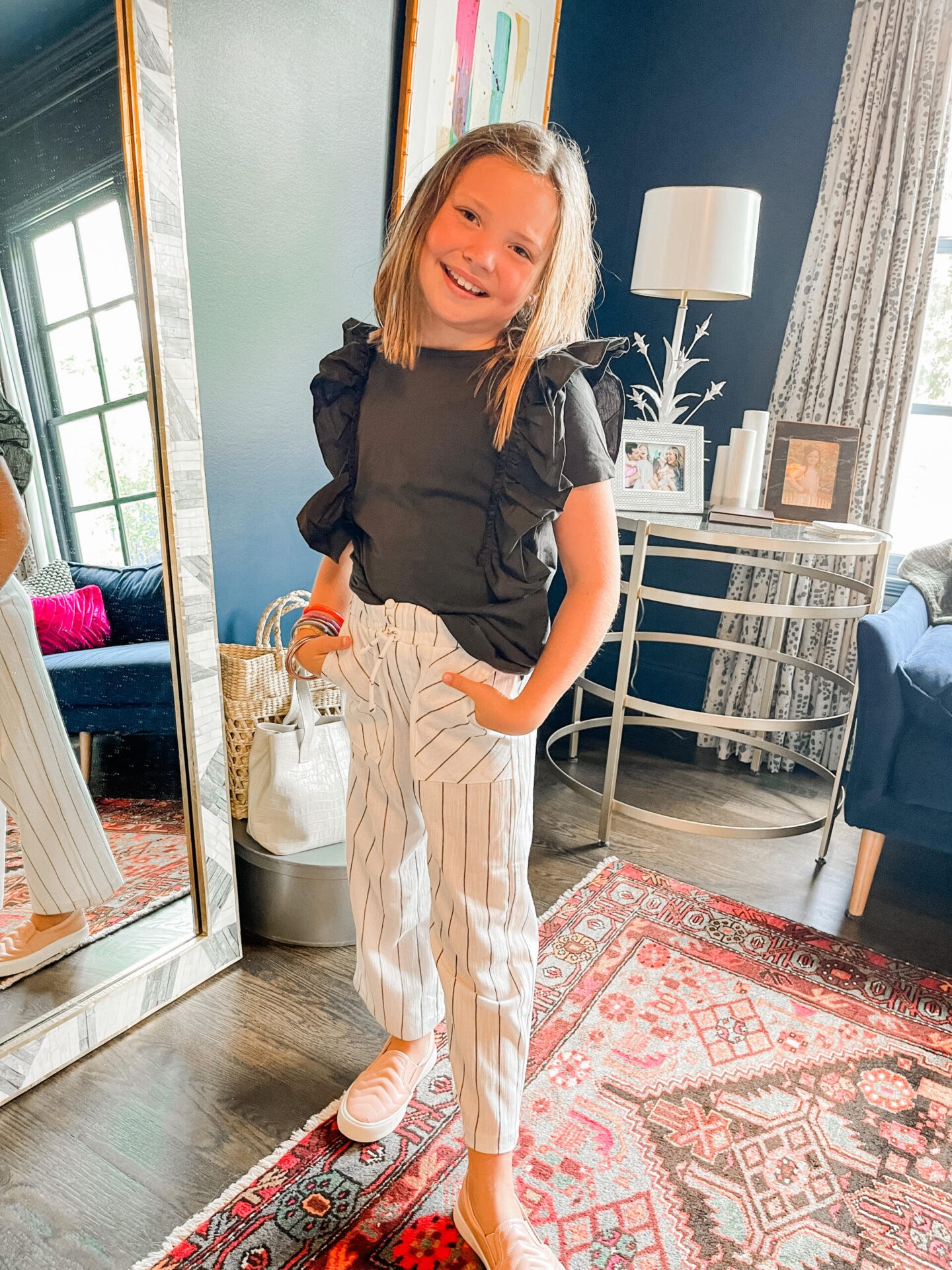 Back to School Essentials by popular Nashville lifestyle blog, Hello Happiness: image of a young girl wearing a black ruffle shirt, black and white drawstring pants, and pink sneakers.