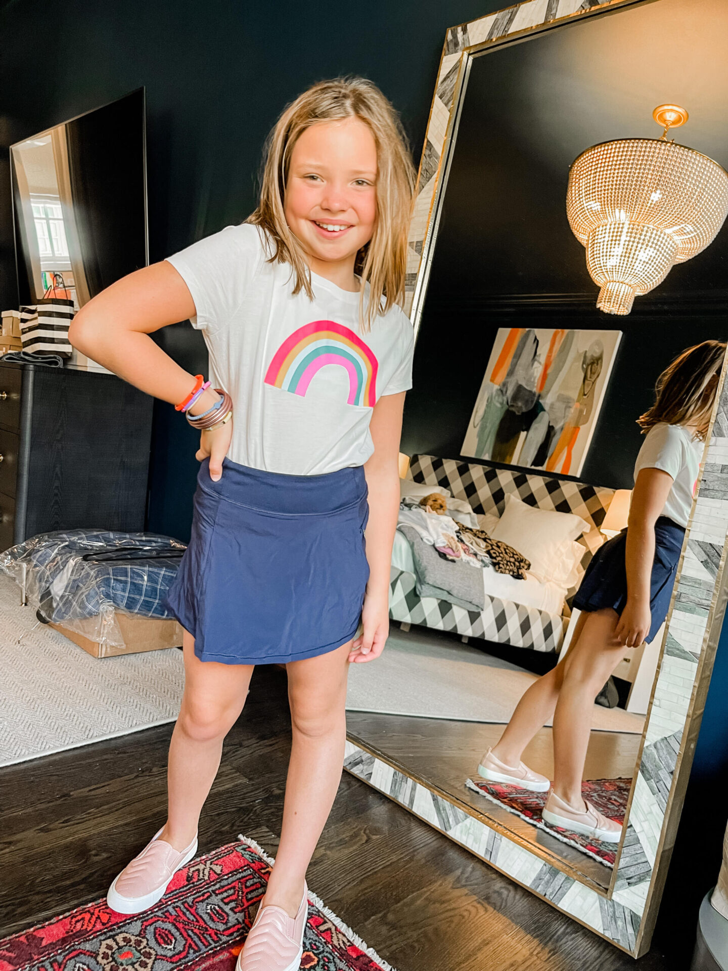 Back to School Essentials by popular Nashville lifestyle blog, Hello Happiness: image of a young girl wearing a rainbow graphic shirt and all in motion skirt with pink sneakers.