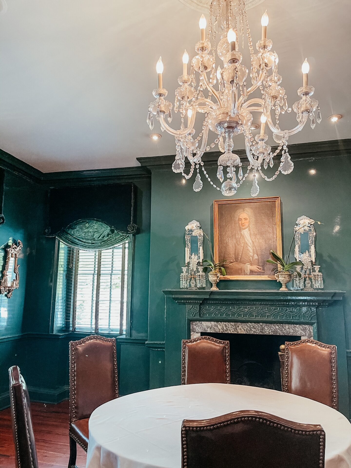 Girls Getaway by popular Nashville travel blog, Hello Happiness: image of room with green walls, green drapes, marble fireplace, and round table with leather chairs.