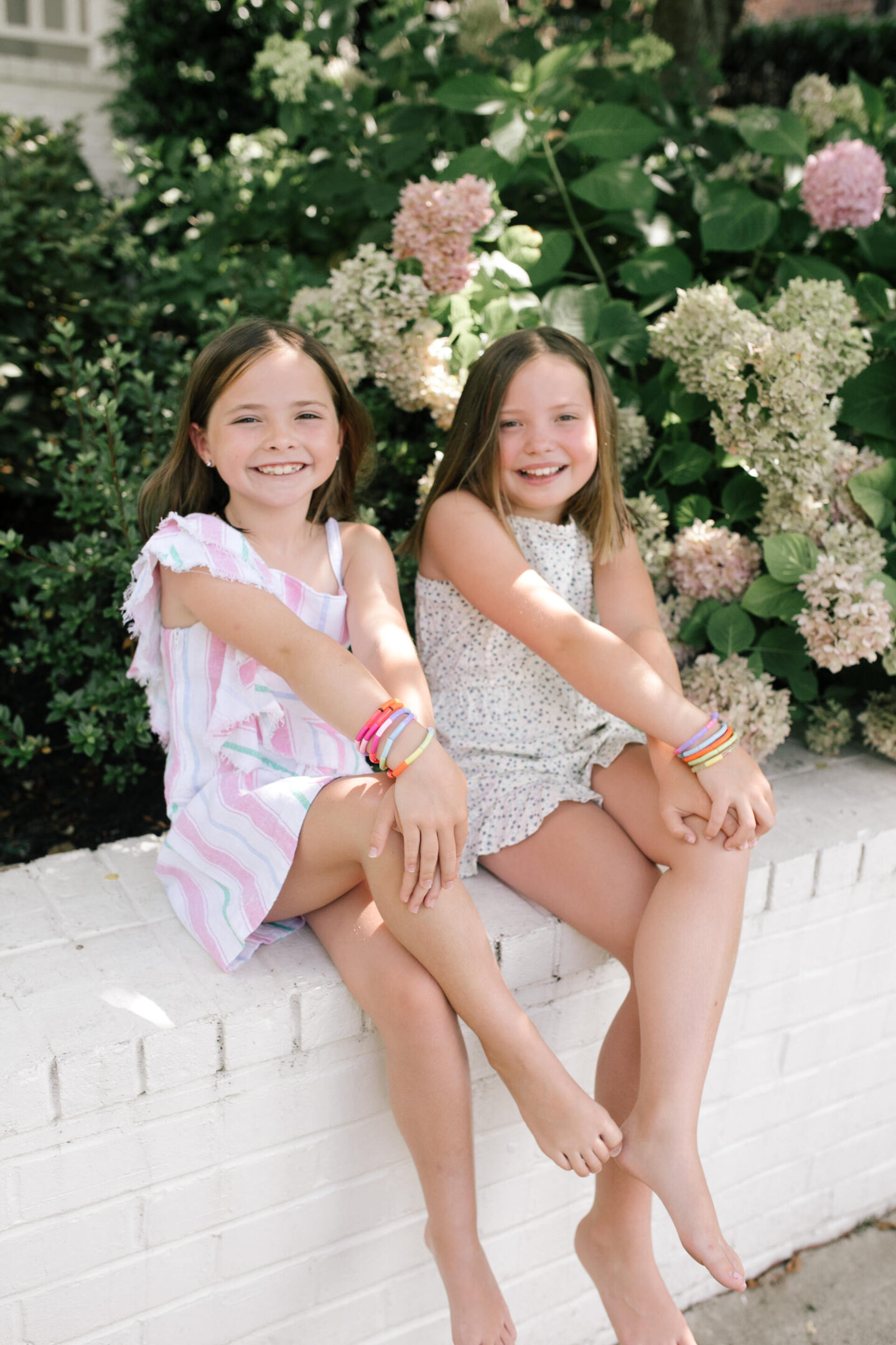 Back to School Essentials by popular Nashville lifestyle blog, Hello Happiness: image of two young girls sitting together and wearing a stripe dress, floral romper, carson stack bracelets and Caroline stack bracelets. 
