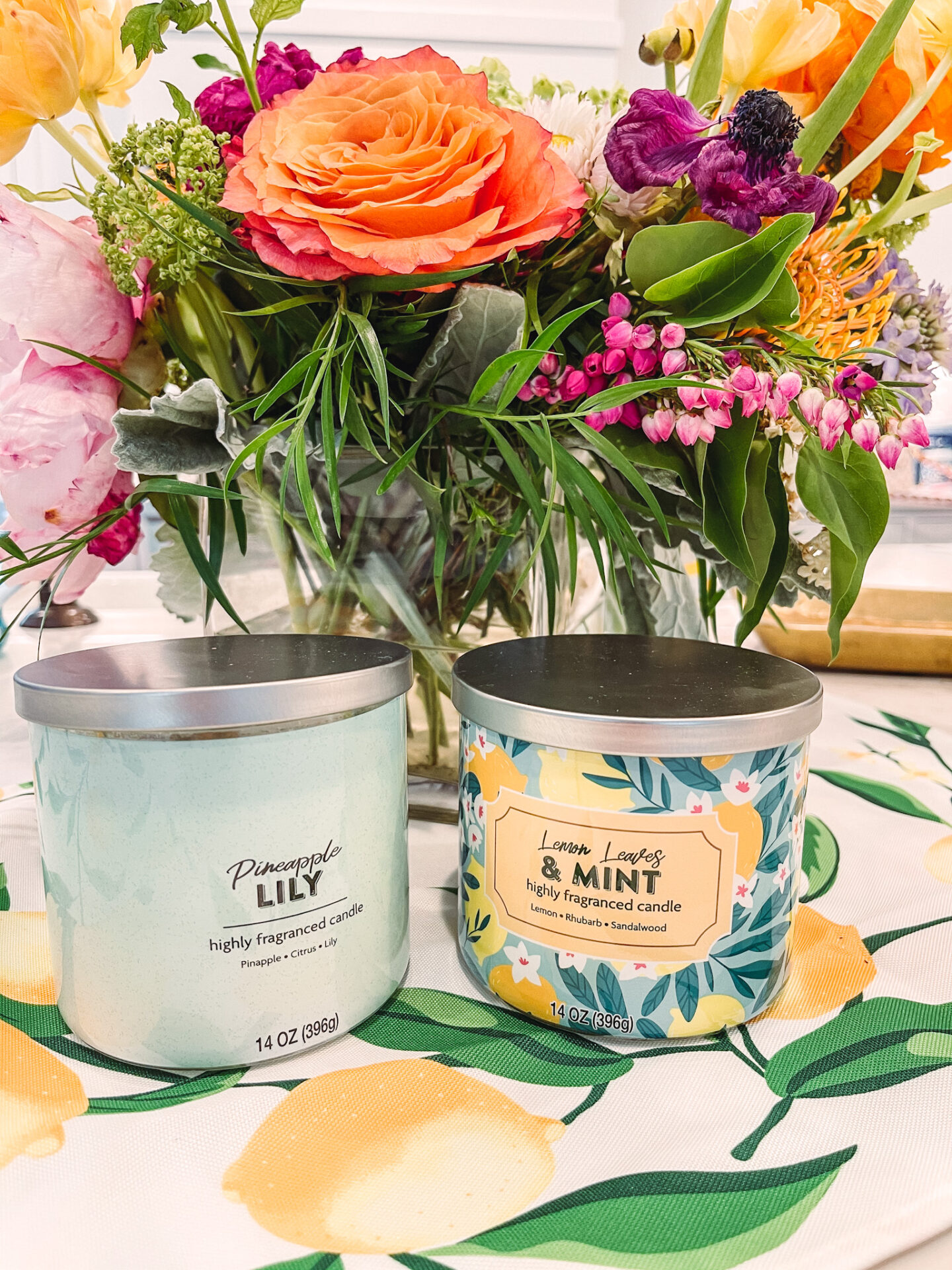 Walmart Summer by popular Nashville life and style blog, Hello Happiness: image of a Pineapple Lilly fragrance candle and a Lemon Leaves and mint fragrance candle next to a vase of flowers. 
