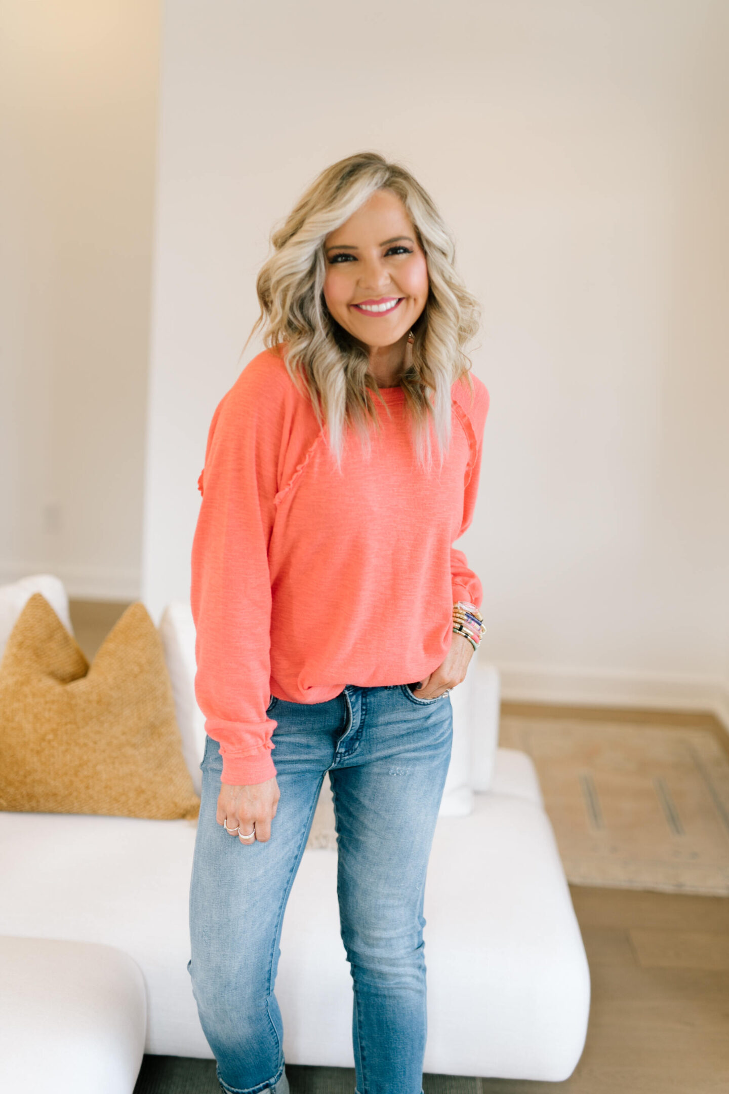 Anthro x Pilcro by popular Nashville fashion blog, Hello Happiness: image of Natasha Stoneking wearing some Anthro x Pilcro jeans, long sleeve orange top and rose gold sneakers.