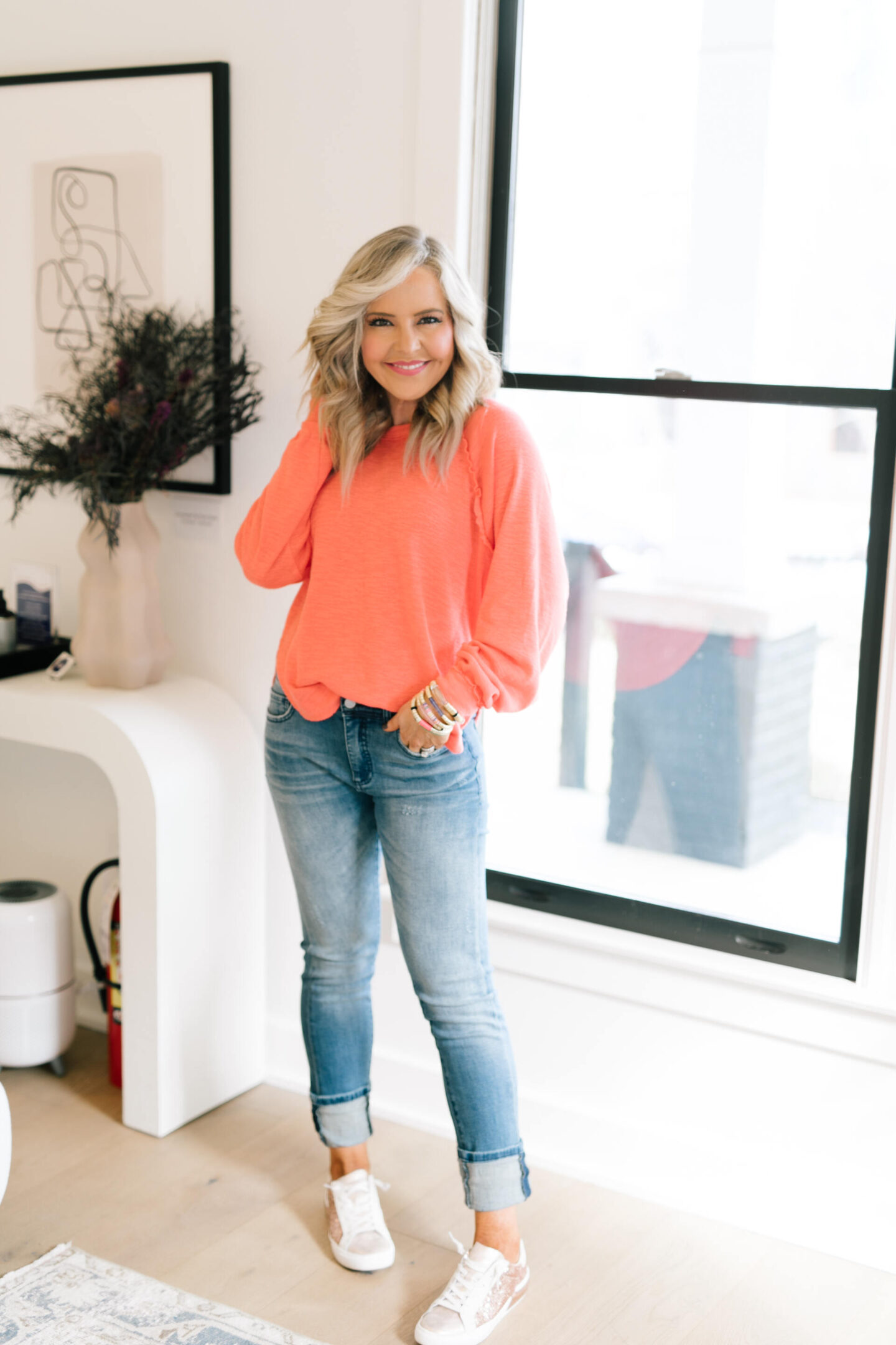 Anthro x Pilcro by popular Nashville fashion blog, Hello Happiness: image of Natasha Stoneking wearing some Anthro x Pilcro jeans, long sleeve orange top and rose gold sneakers.