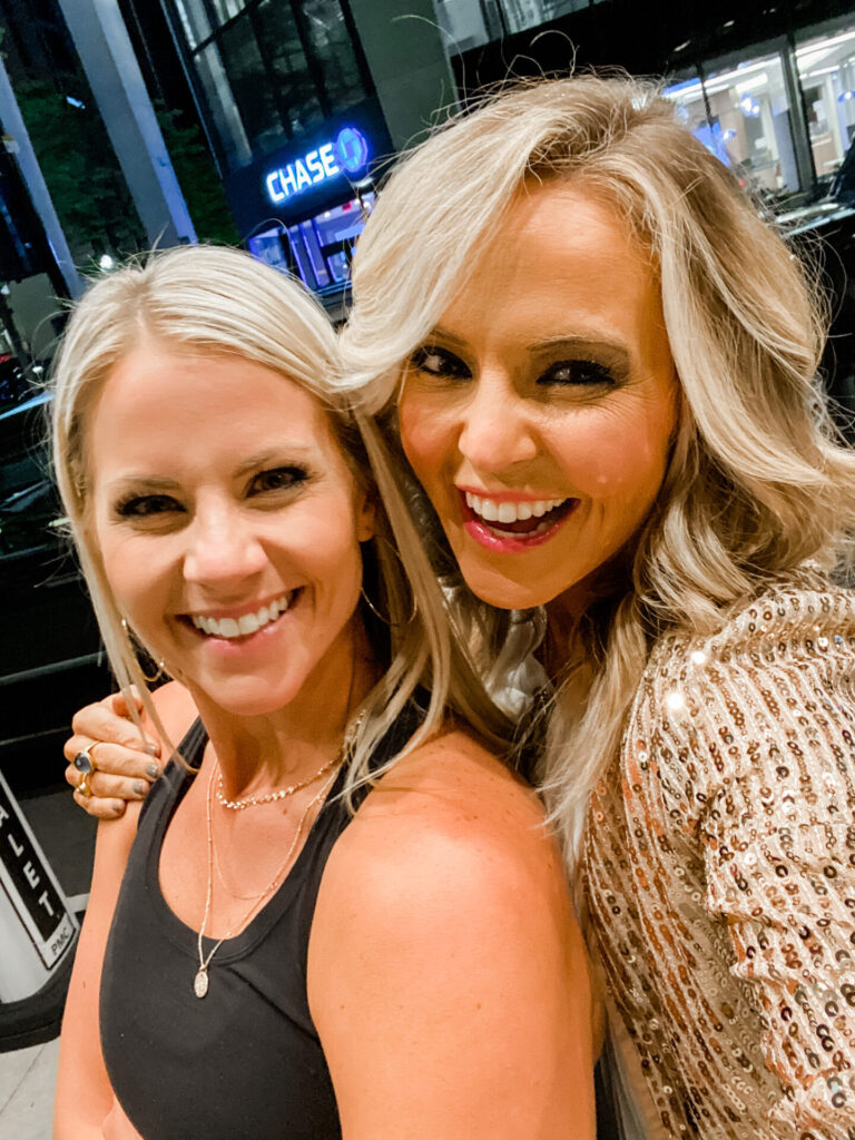 Staycation Ideas by popular Nashville travel blog, Hello Happiness: image of two women wearing a black tank top and sequin jacket and standing together outside. 