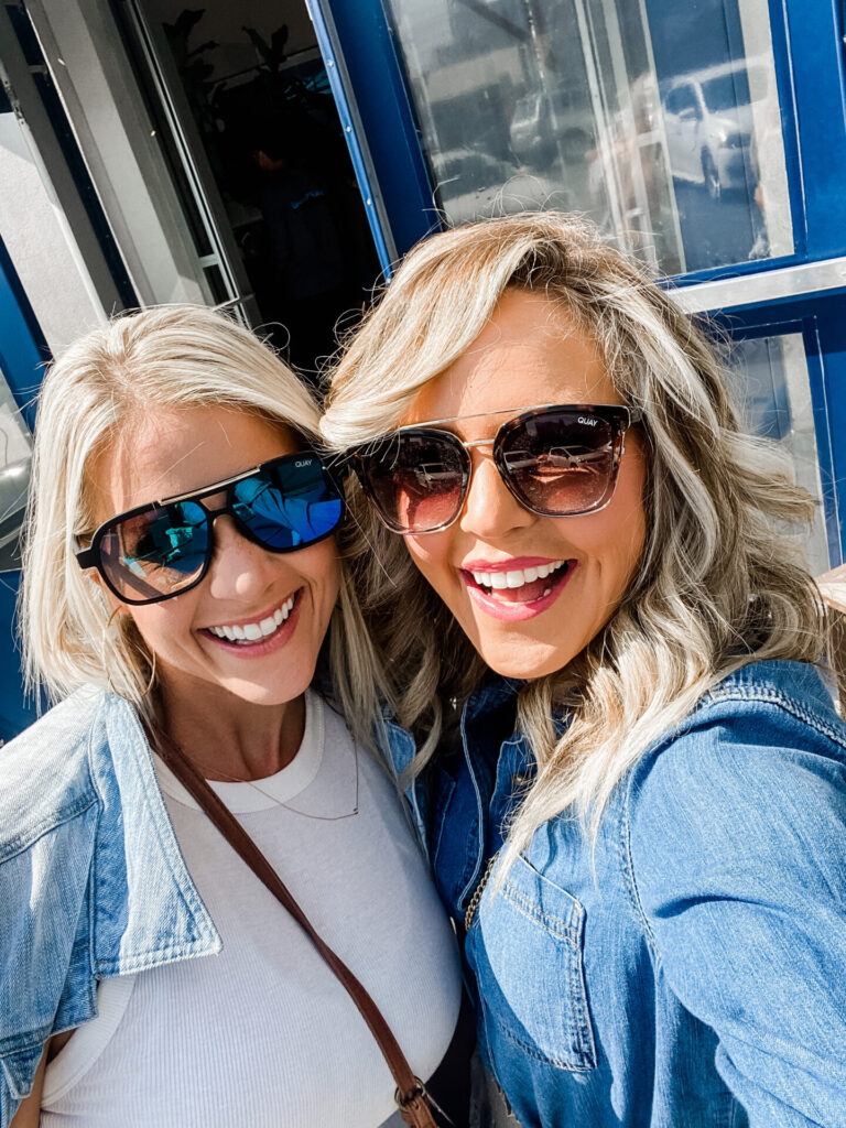 Staycation Ideas by popular Nashville travel blog, Hello Happiness: image of two women wearing Quay Australia sunglasses and denim tops and standing together while they take a selfie. 