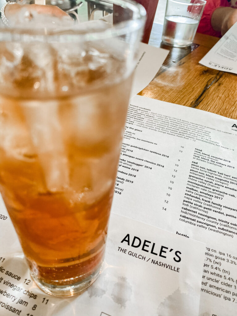 Staycation Ideas by popular Nashville travel blog, Hello Happiness: image of a drink standing on top of a Adele's The Gulch Nashville restaurant menu. 