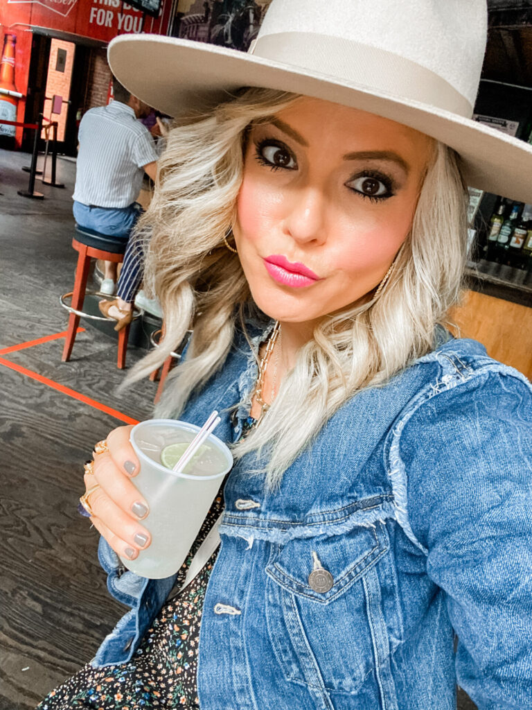 Staycation Ideas by popular Nashville travel blog, Hello Happiness: image of a woman wearing a Urban Outfitters Flat Brim Felt Fedora, Target Women's Puff Short Sleeve Dress, Able MARGARIT RAW EDGE JACKET, Vince Camuto DEVENA WESTERN BOOTIE, Gucci purse, Julie Vos Cascade Hoop, and Quay Australia sunglasses and holding a alcoholic drink.    