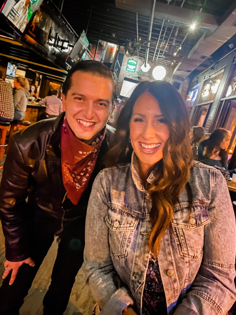Staycation Ideas by popular Nashville travel blog, Hello Happiness: image of a woman and a man standing next to each other in a bar.   