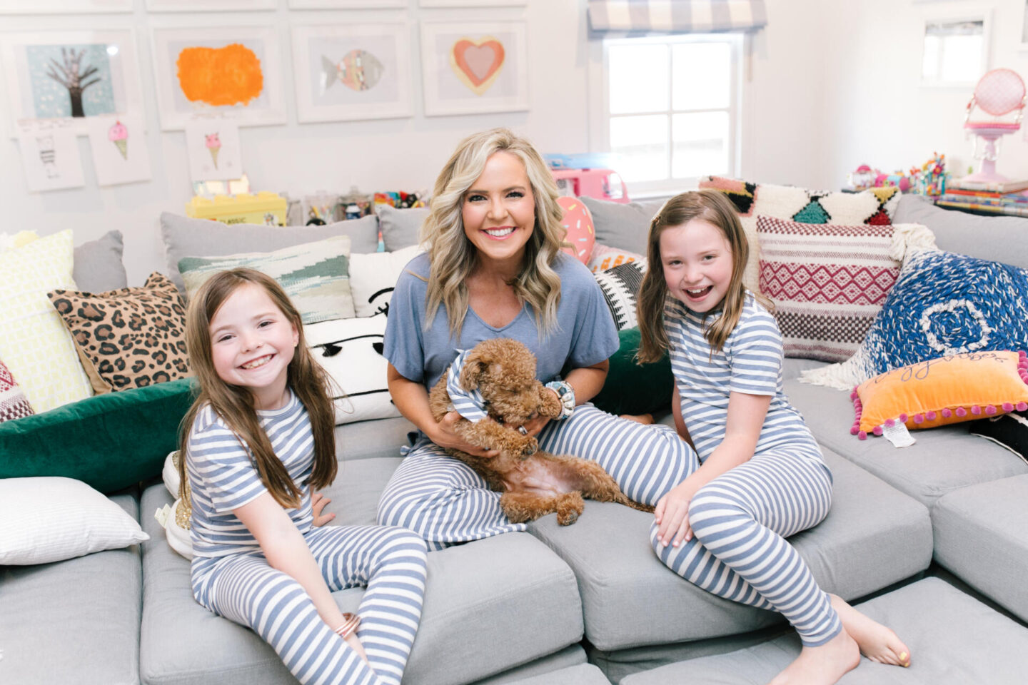 Mommy and Me Pajamas by popular Nashville fashion blog, Hello Happiness: image of a mom and her daughter sitting on a sectional couch with their goldendoodle puppy and wearing blue and white stripe Soma Intimates mommy and me pajamas. 