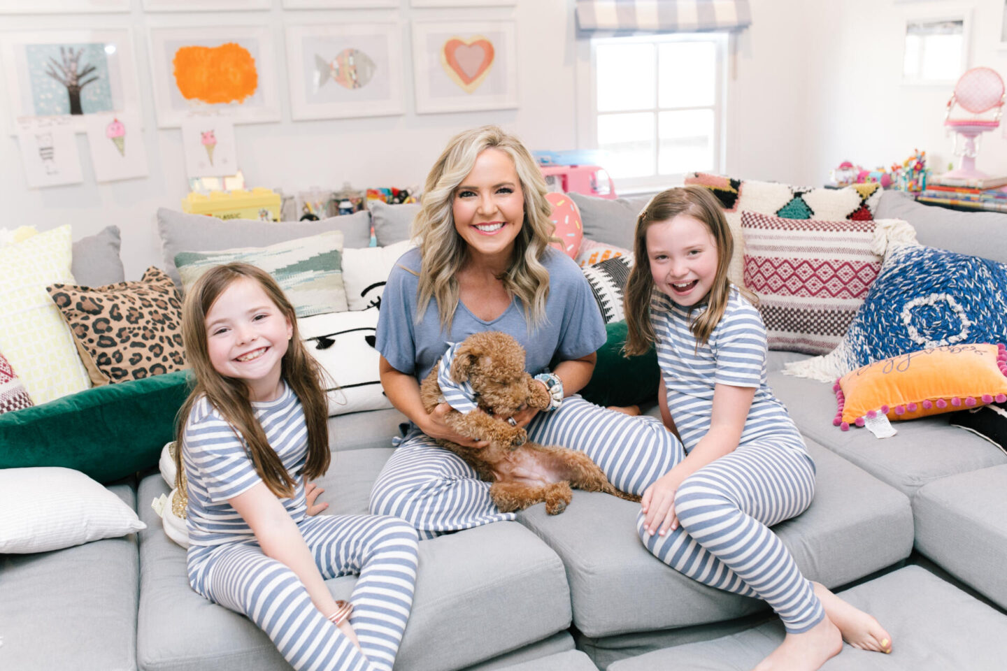 Mommy and Me Pajamas by popular Nashville fashion blog, Hello Happiness: image of a mom and her daughter sitting on a sectional couch with their goldendoodle puppy and wearing blue and white stripe Soma Intimates mommy and me pajamas.