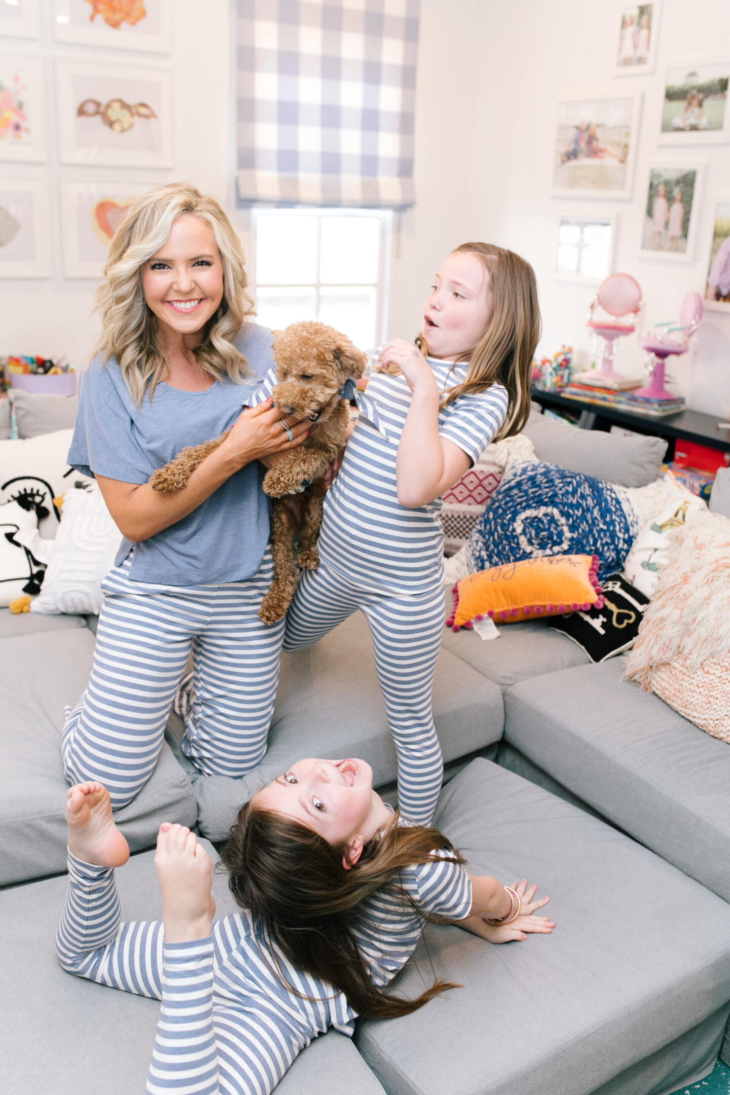 Mommy and Me Pajamas by popular Nashville fashion blog, Hello Happiness: image of a mom and her daughter sitting on a sectional couch with their goldendoodle puppy and wearing blue and white stripe Soma Intimates mommy and me pajamas.