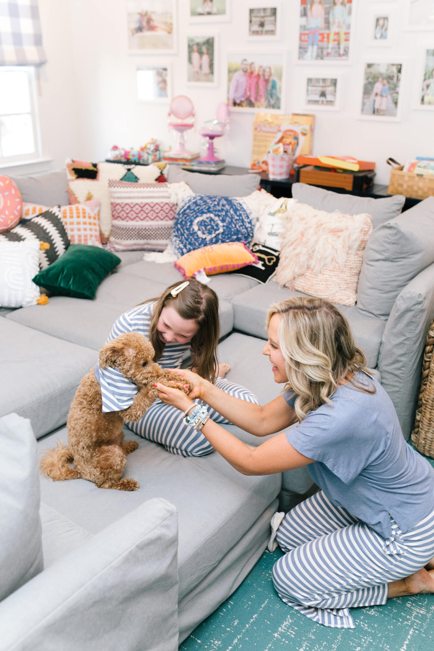 Mommy and Me Pajamas by popular Nashville fashion blog, Hello Happiness: image of a mom and her daughter sitting on a sectional couch with their goldendoodle puppy and wearing blue and white stripe Soma Intimates mommy and me pajamas.