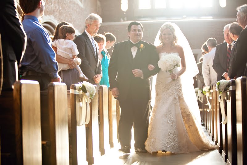 10 Year Wedding Anniversary by popular Nashville lifestyle blog, Hello Happiness: image of a bride wearing a strapless lace bride gown and veil and being walked down an aisle by her father who's wearing a black tuxedo and. yellow rose boutonniere.