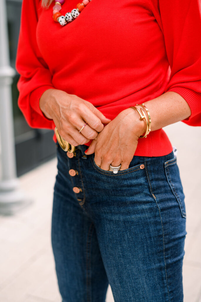 Accessory Concierge by popular Nashville fashion blog, Hello Happiness: image of Natasha Stoneking wearing the Accessory Concierge Natasha Beaded Necklace, Nailed It Bracelet, Pyramind Spike Hinge Bracelet, Red Puff Sleeve Sweater, Crop Demi Boot Jeans, and Black Gucci Belt