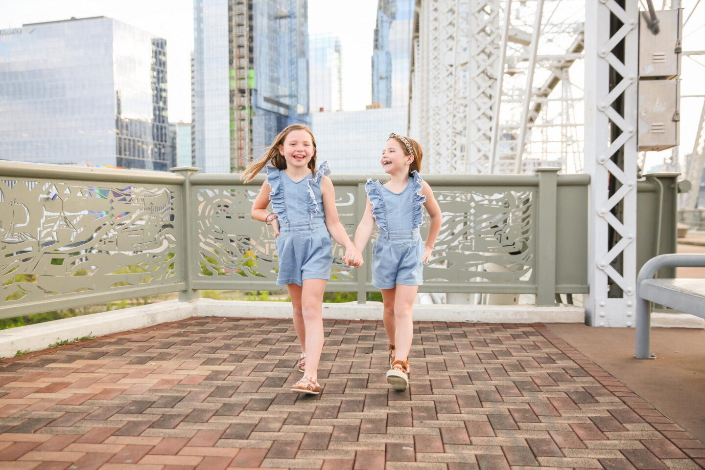 Summer Bucket List by popular Nashville lifestyle blog, Hello Happiness: image of two young girls holding hands and wearing matching chambray rompers and brown sandals.
