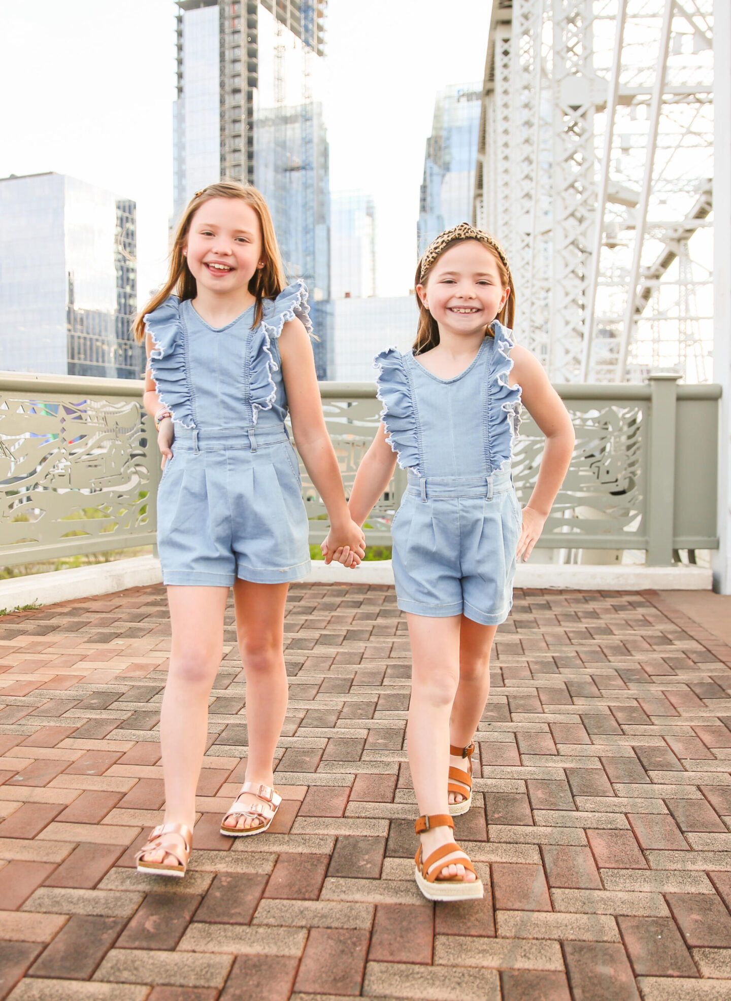 Summer Bucket List by popular Nashville lifestyle blog, Hello Happiness: image of two young girls holding hands and wearing matching chambray rompers and brown sandals.