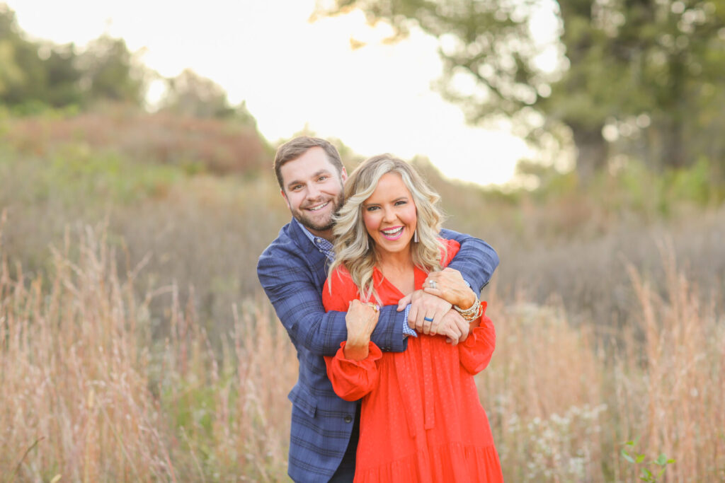 Relationship Advice by popular Nashville lifestyle blog, Hello Happiness: image of a husband and wife standing together in a field and wearing a tiered red maxi dress and blue plaid blazer. 
