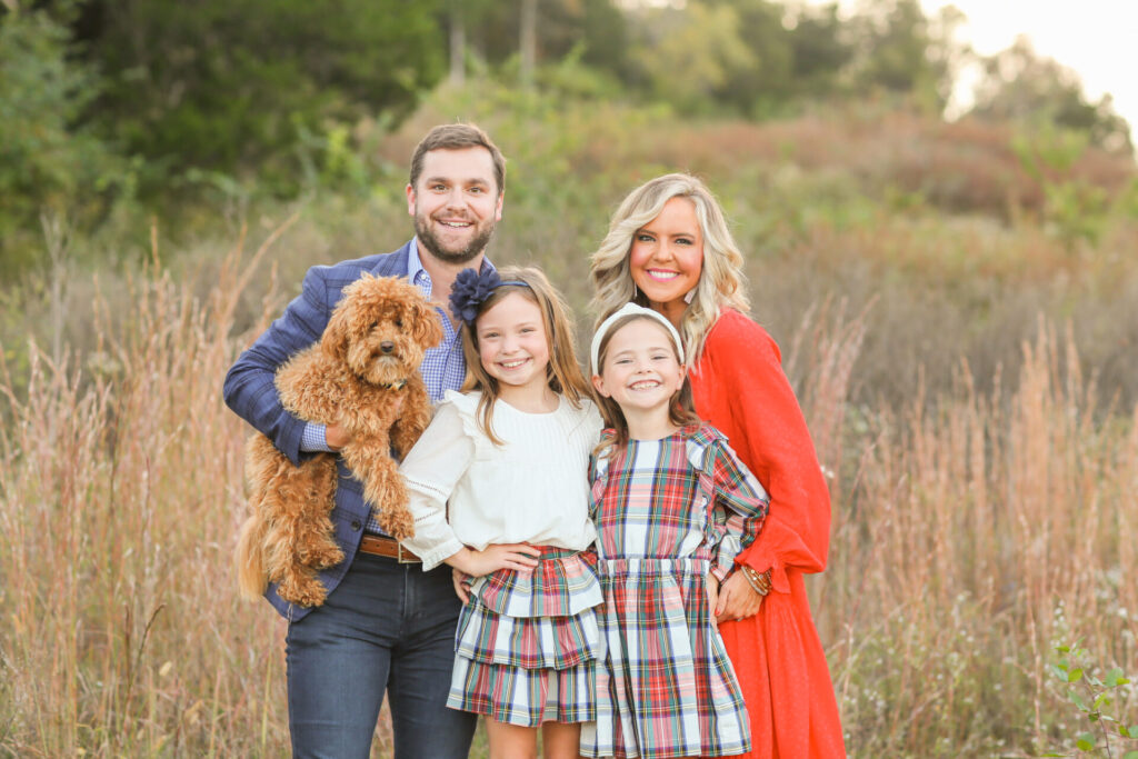 Relationship Advice by popular Nashville lifestyle blog, Hello Happiness: image of a husband and wife standing together in a field with their two daughters and their dog and wearing a tiered red maxi dress, blue plaid blazer, plaid ruffle dress, plaid tiered skirt, and cream ruffle blouse. 